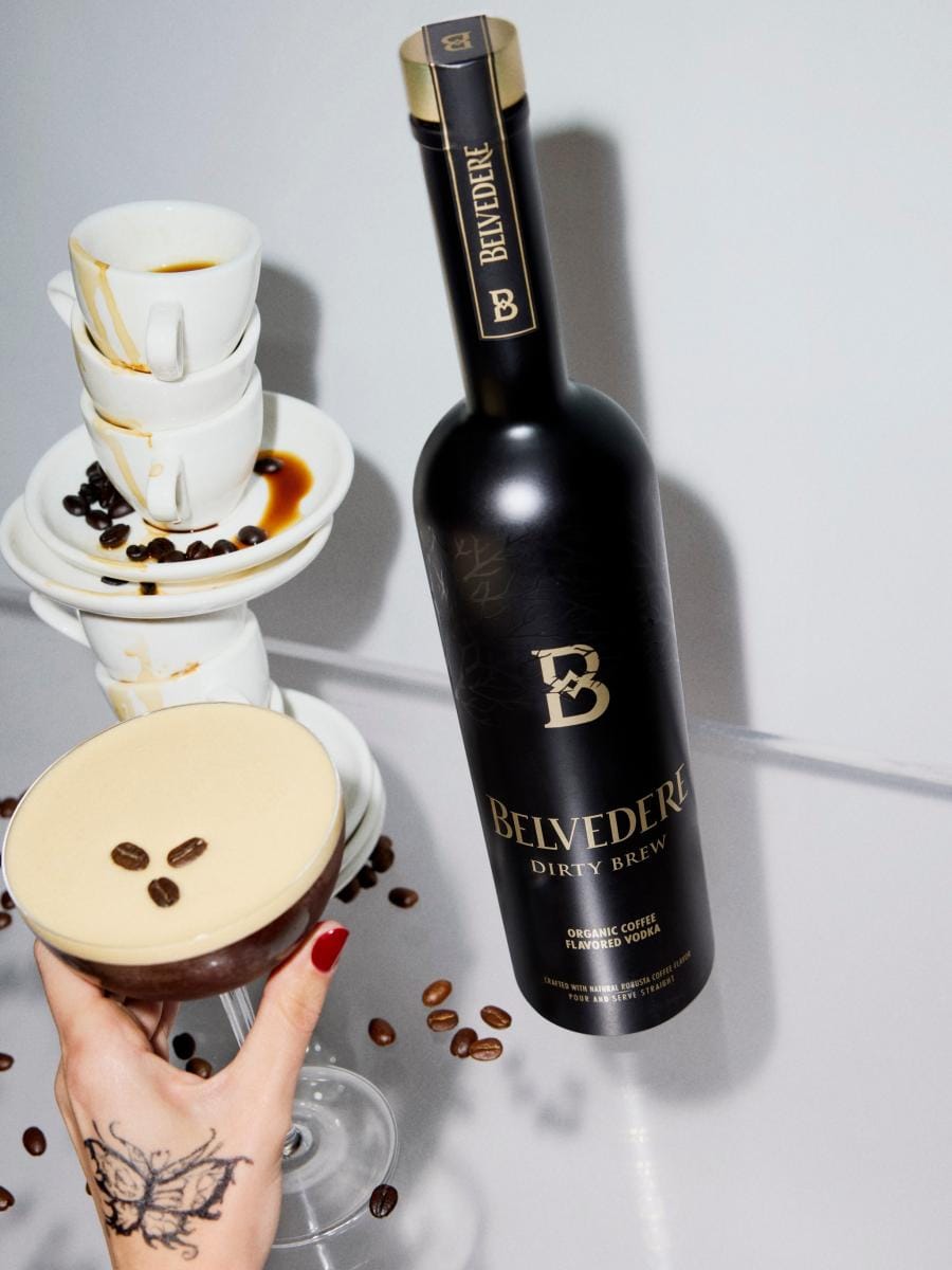 Bottle of Belvedere Dirty Brew next to a Dirty Espresso Martini and stacked coffee cups