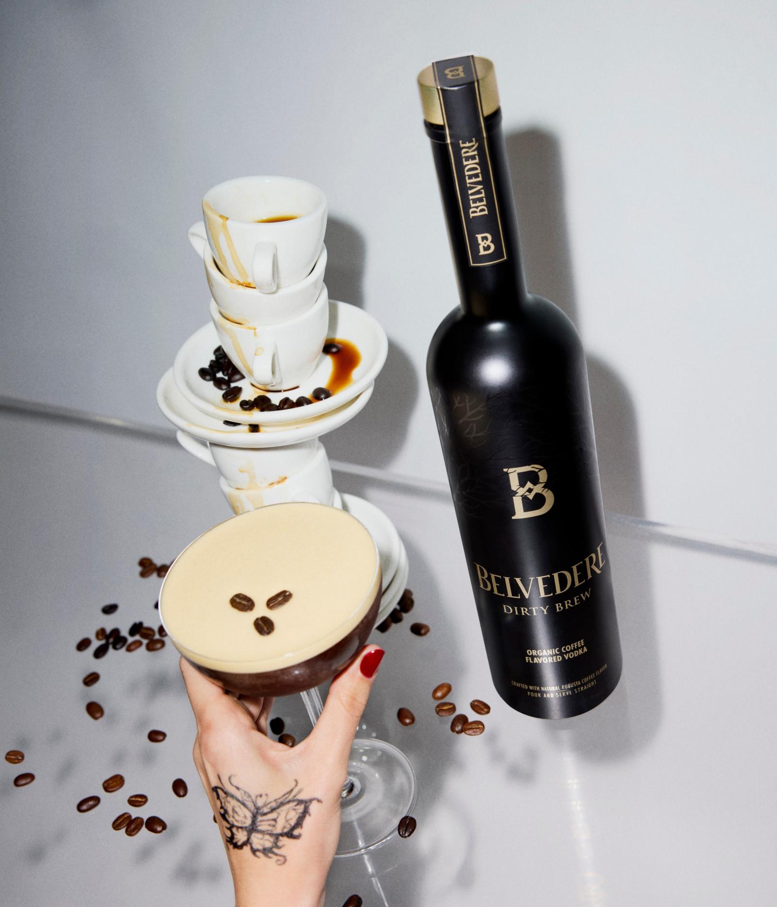 Bottle of Belvedere Dirty Brew next to a Dirty Espresso Martini and stacked coffee cups
