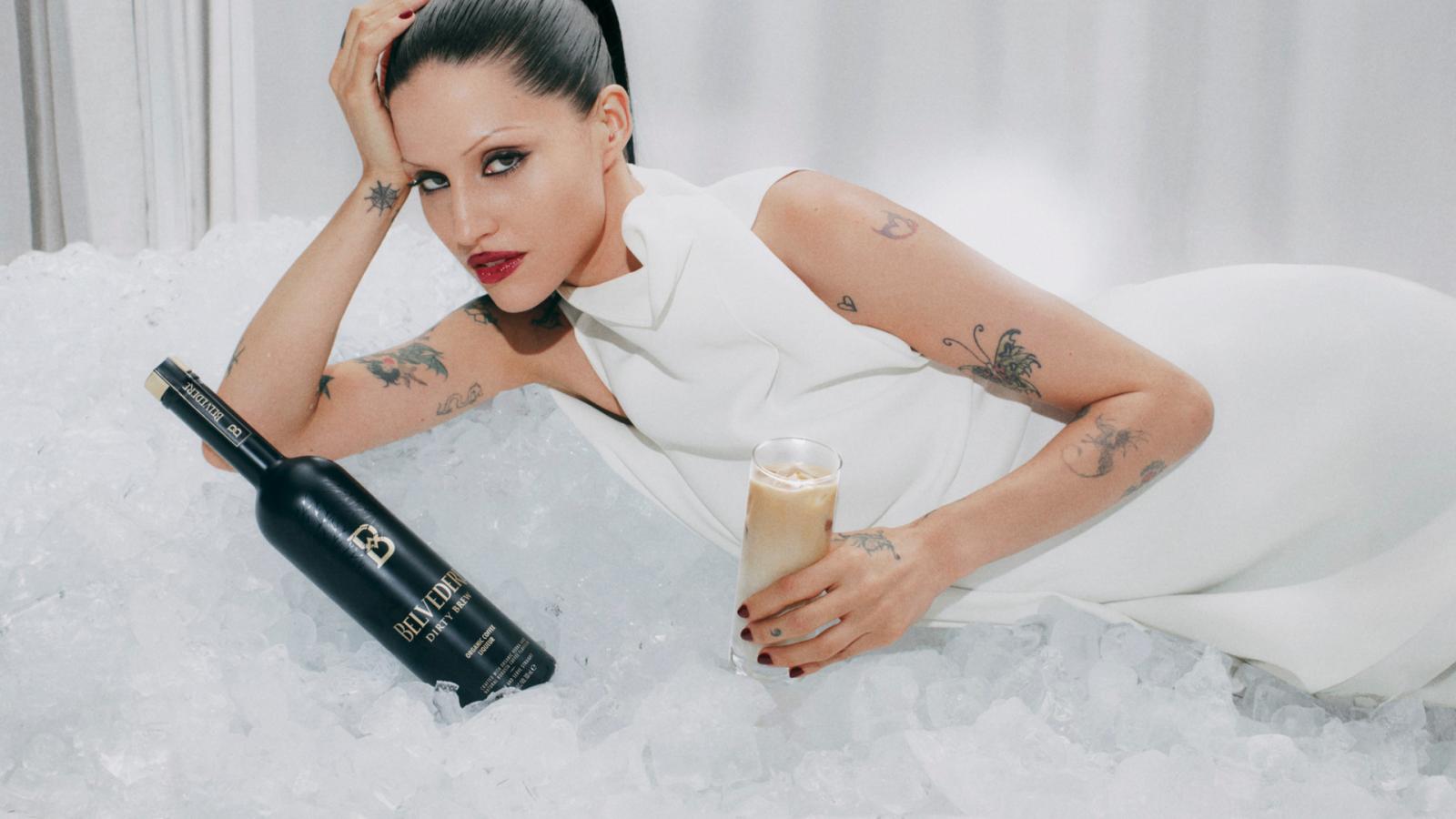 Gabbriette lying on ice with a bottle of Belvedere Dirty Brew and a Dirty Latte